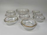 six bols en verre transparent aux bords dorés sont disposés sur une surface blanche