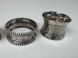 three silver napkins and a silver cup on a white surface