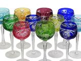 six colorful wine glasses are lined up on a white surface