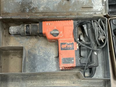 une perceuse orange dans un coffret contenant d'autres outils