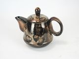 a small tea pot with a handle on a white surface