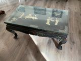 une table basse avec un plateau en verre posée sur un parquet