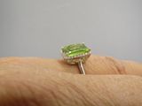 une image représentant la main d'une personne tenant une bague sertie d'une pierre verte