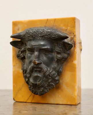 an image of a statue of a man with a beard and a goat ' s head on a marble block