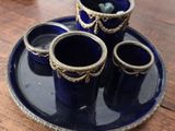 quatre tasses bleues posées sur une assiette bleue, sur une table en bois