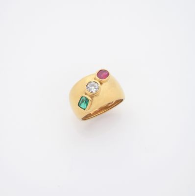 un gros plan d'une bague en or sertie d'une pierre verte et rouge