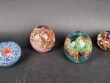 four glass marbles sitting on top of a black surface