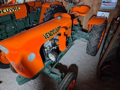 orange and green tractor parked in a garage next to a wooden wall