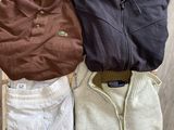 trois pulls pour homme posés sur une caisse en bois