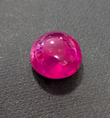 a close up of a pink stone on a black surface