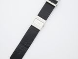 gros plan d'une montre sur une surface blanche avec un bracelet noir