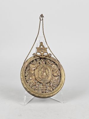 a gold plate with a bird on it hanging from a rope
