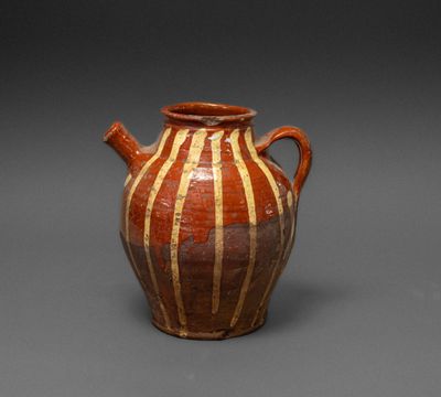 brown and white vase with stripes on it on a gray surface