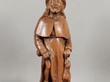 une vieille statue en bois représentant un homme avec un chapeau et une canne