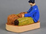 a figurine of a man with a basket on his lap
