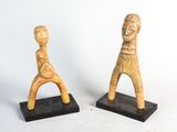 paire de figurines en bois représentant un homme et une femme, posées sur des socles noirs