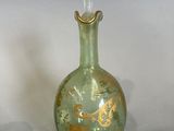 a green glass bottle with a gold design on it