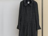 un manteau noir et blanc suspendu à un cintre près d'un mur