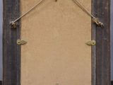an old picture frame hanging on a wall with a string