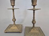 paire de bougeoirs anciens en laiton, dont les socles sont ornés de motifs élaborés