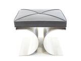 un pouf en cuir noir posé sur une table blanche