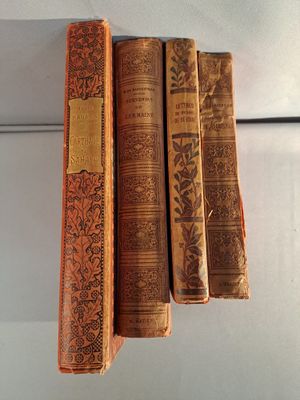 trois vieux livres sont empilés les uns sur les autres sur une étagère