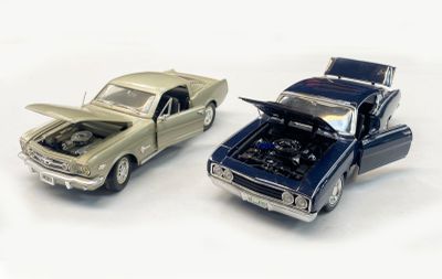 two toy cars that are next to each other on a white surface