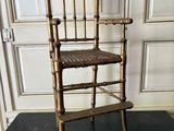 a wooden chair with a woven seat on a black floor