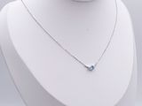 silver necklace with a blue topaz stone on a white mannequin