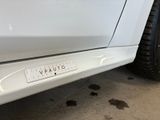 the rear end of a white car with a sticker on it ' s bumper