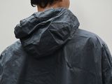 man wearing a black jacket with a hood and a black hat