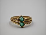 gros plan d'une bague en or avec une pierre verte