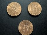 three gold coins sitting on top of a black surface