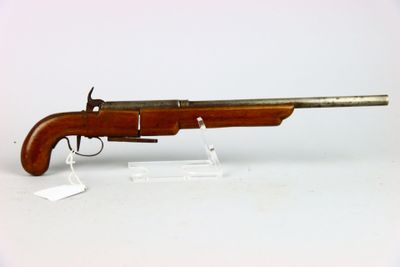 un vieux pistolet au canon en bois posé sur une surface blanche