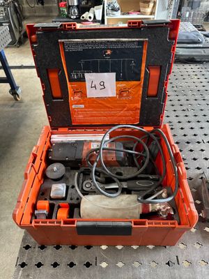 une boîte à outils orange posée par terre, contenant des outils
