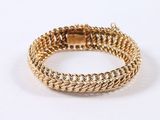 a close up of a gold chain bracelet on a white background