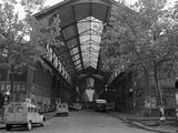 black and white photograph of an old train station with cars parked in front of it