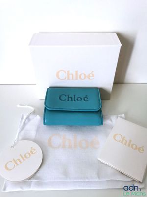 un sac à main bleu posé sur une table à côté d'une boîte blanche