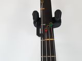 an overhead view of a bass guitar neck with a red and green button