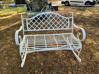 un banc en métal blanc posé au milieu d'un champ