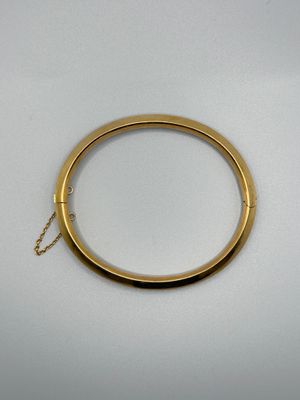gros plan d'un bracelet en or sur une surface blanche