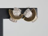 a pair of gold and silver earrings on a black stand