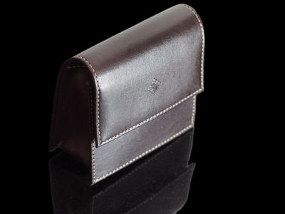 étui à cartes de visite en cuir posé sur une surface noire avec des reflets