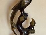 une statue représentant un oiseau sur une branche, sur laquelle est perché un autre oiseau