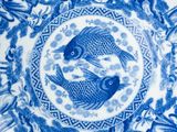 blue and white plate with two birds in a circle surrounded by palm trees