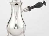 une cafetière ancienne en argent avec une poignée noire sur fond blanc