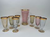 six glasses and a pitcher sitting on a table