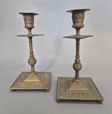 paire de bougeoirs anciens en laiton, dont les socles sont ornés de motifs élaborés