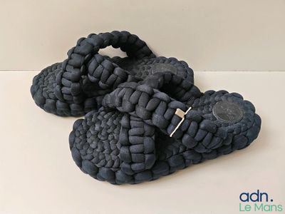 a pair of black sandals that are on a white surface