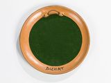 a brown plate with a green lid on a white surface